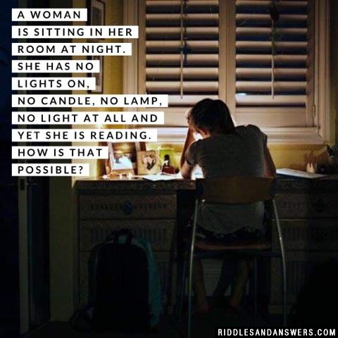 A woman is sitting in her room at night. She has no lights on, no candle, no lamp, no light at all and yet she is reading. How is that possible?